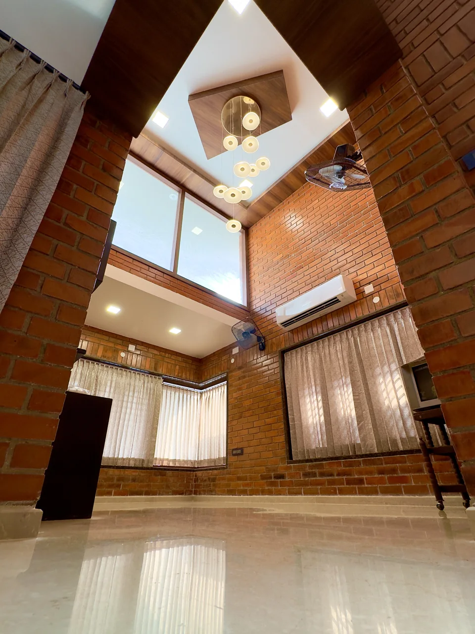 Double-height living space with exposed brick walls, high windows and a polished floor