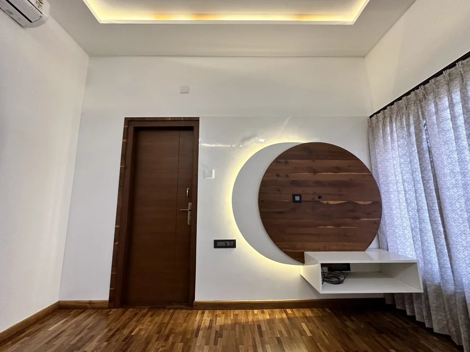 Bedroom with timber flooring and a round wood panel framed by a backlit crescent