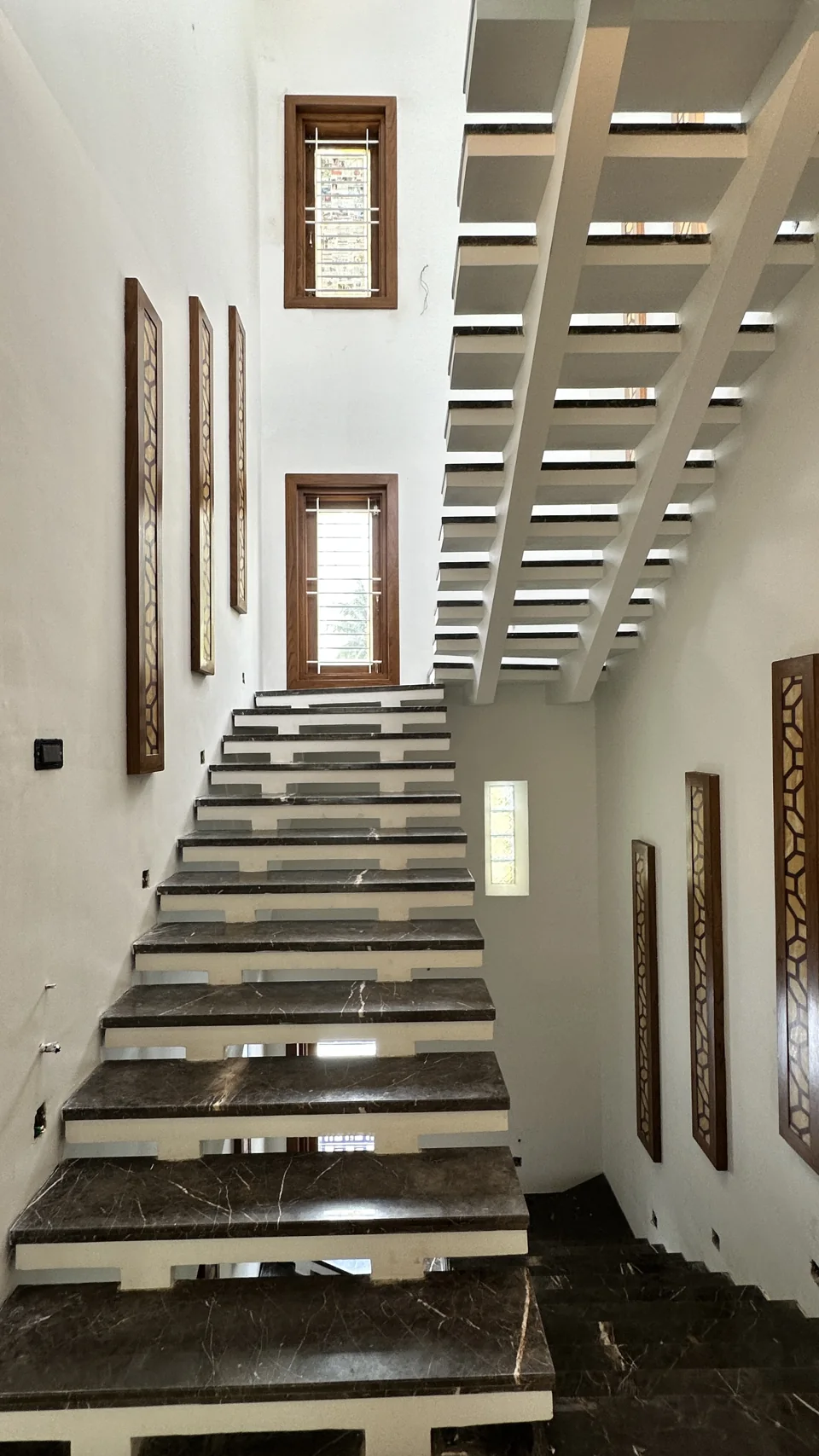 Interior staircase beneath a geometric roof opening with white walls